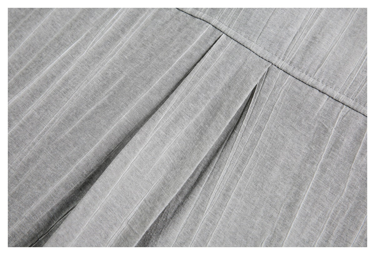 Close-up of gray subtly striped fabric with a stitched seam and a folded pleat.