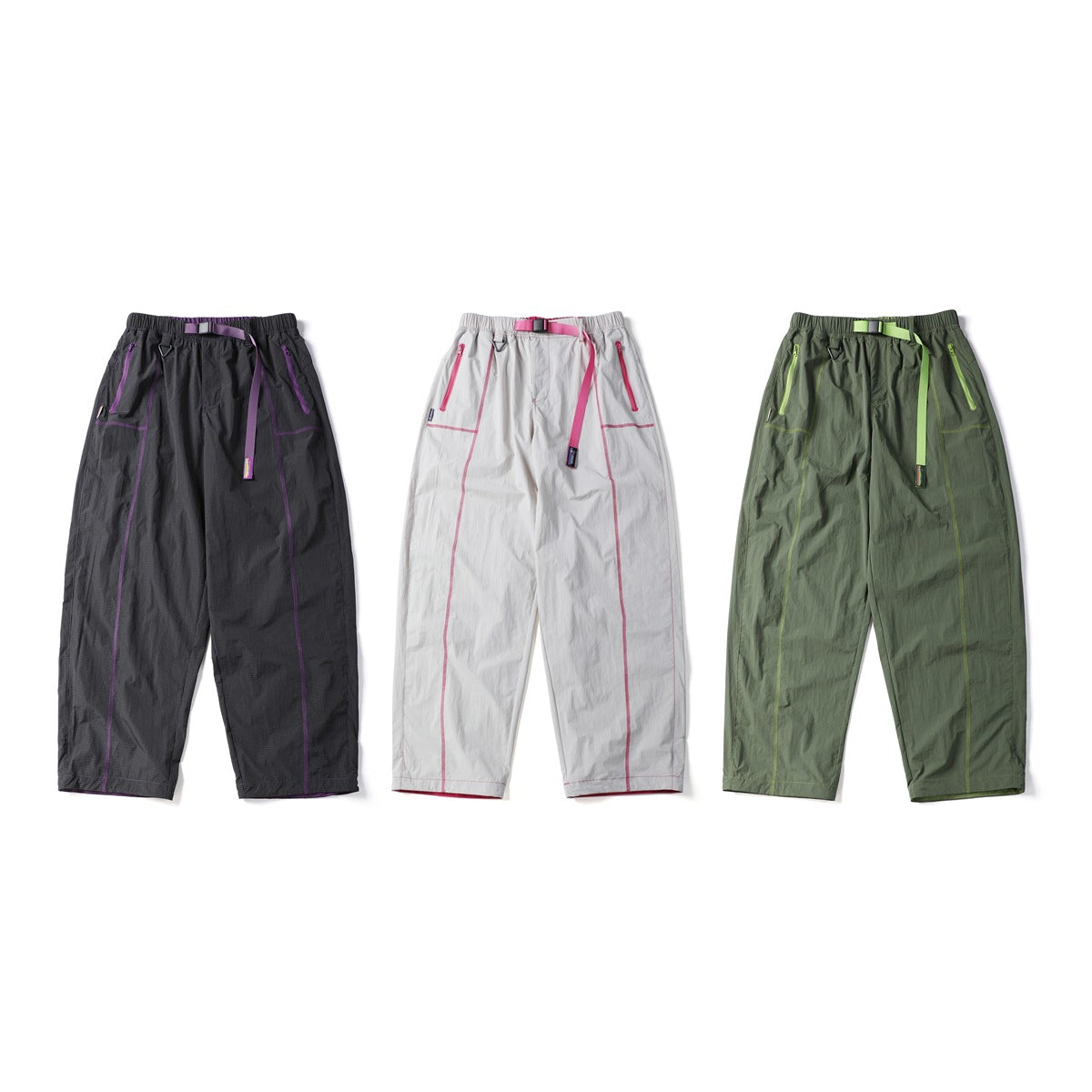 Three pairs of loose trousers shown from the front in charcoal with purple trim, white with pink trim and olive with lime