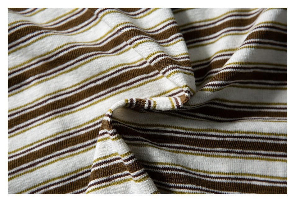 Close-up of cream fabric with brown and olive stripes draped to show its texture and folds.