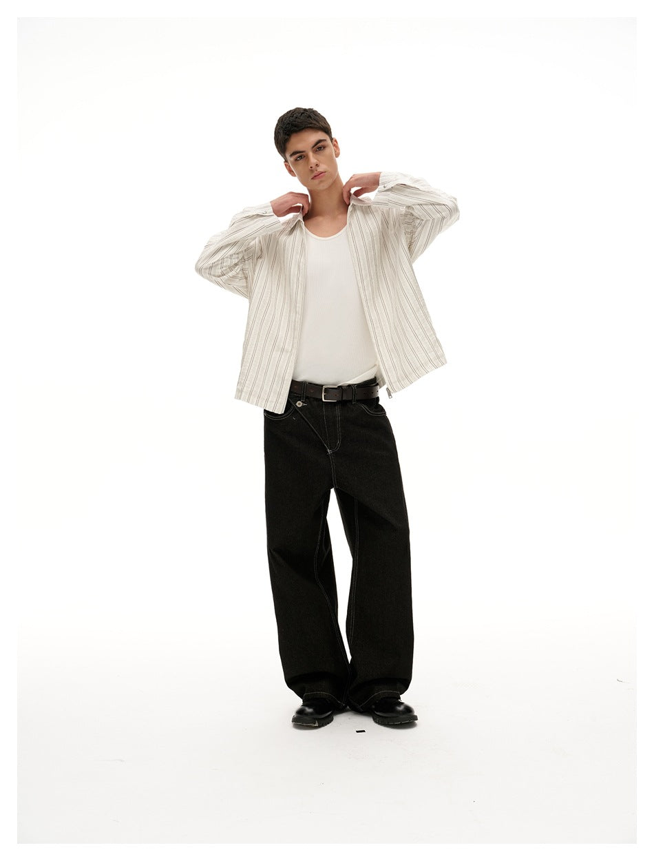 Model wearing open cream pinstriped jacket, hands at collar, with white tank top and black jeans
