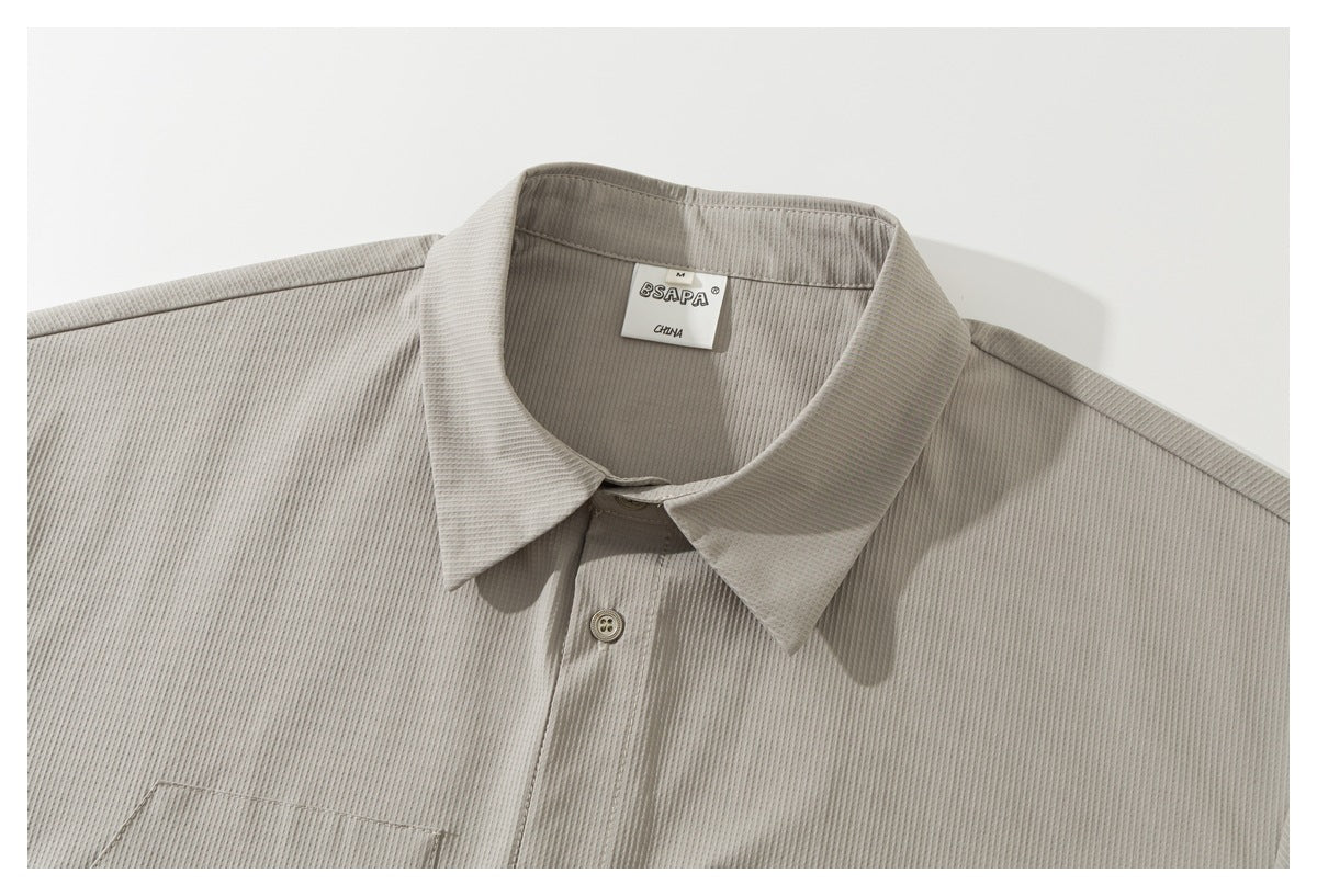 Close-up of a light taupe ribbed button-up shirt showing its pointed collar, front placket, and sewn-in neck label.