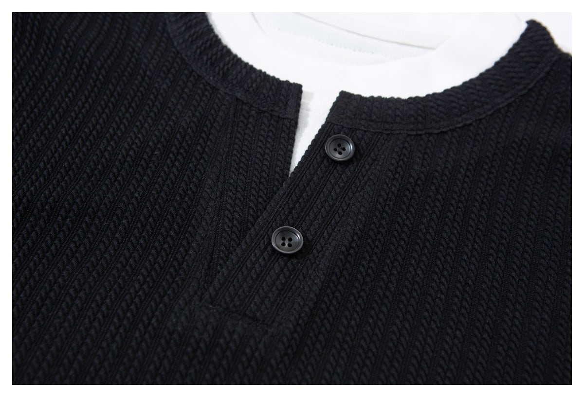 Close-up of a black textured knit garment with a round neckline and two-button placket.