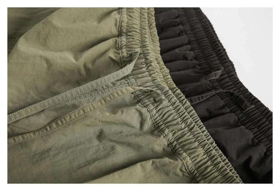 Close-up of olive and charcoal shorts showing elastic waistbands, drawstrings and ripstop fabric.