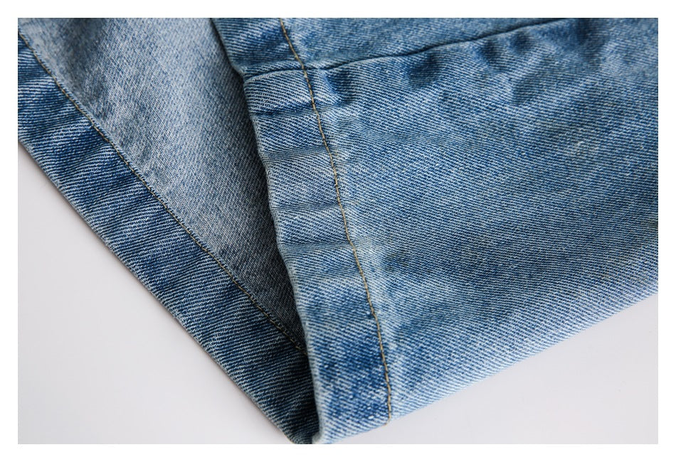 Close-up of folded light blue denim showing the leg seam and faded wash.
