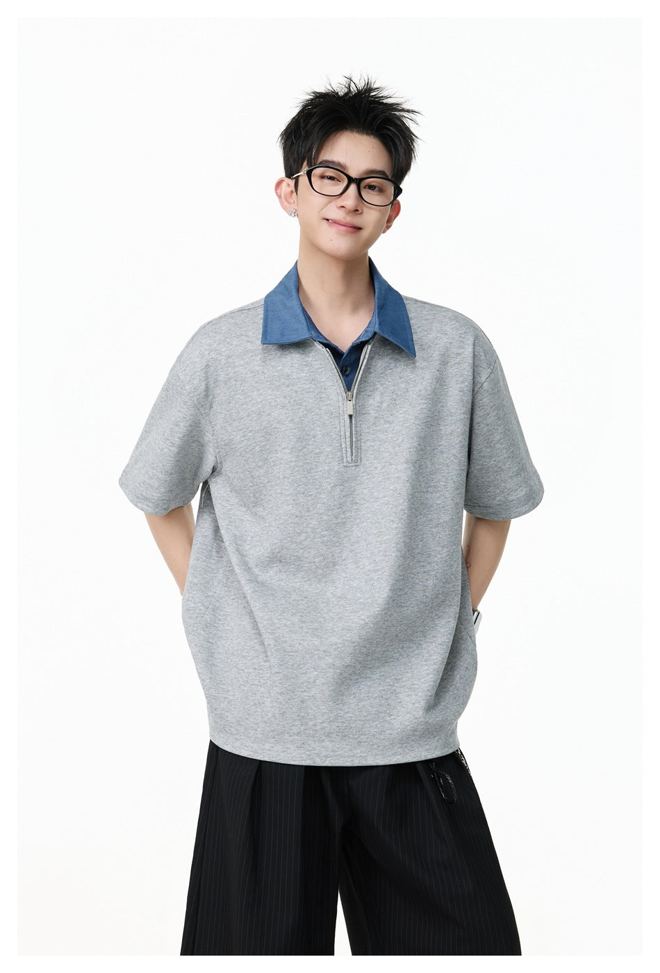 Closer view of a model in an oversized gray top with a blue collar and short zip placket.