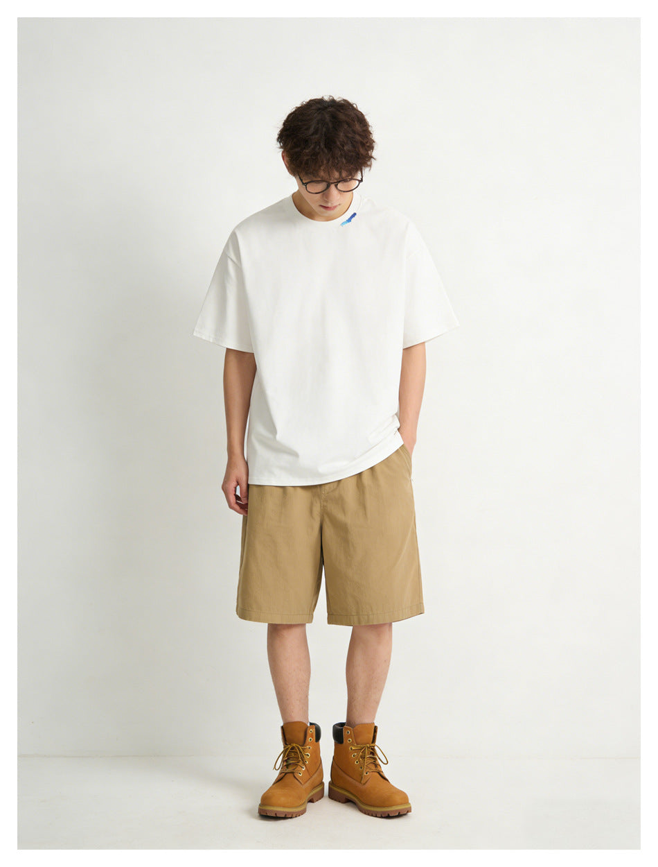 Front view of a model in an oversized white T-shirt, tan shorts, and brown lace-up boots.