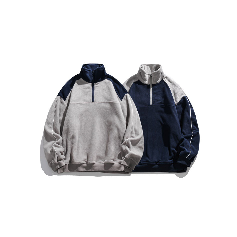 Two colorways of a long-sleeve, high-collar quarter-zip fleece pullover, one light gray with navy panels and one reversed.