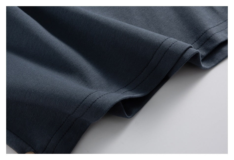 Close-up of a double-stitched hem and folded edge on dark slate-gray fabric.