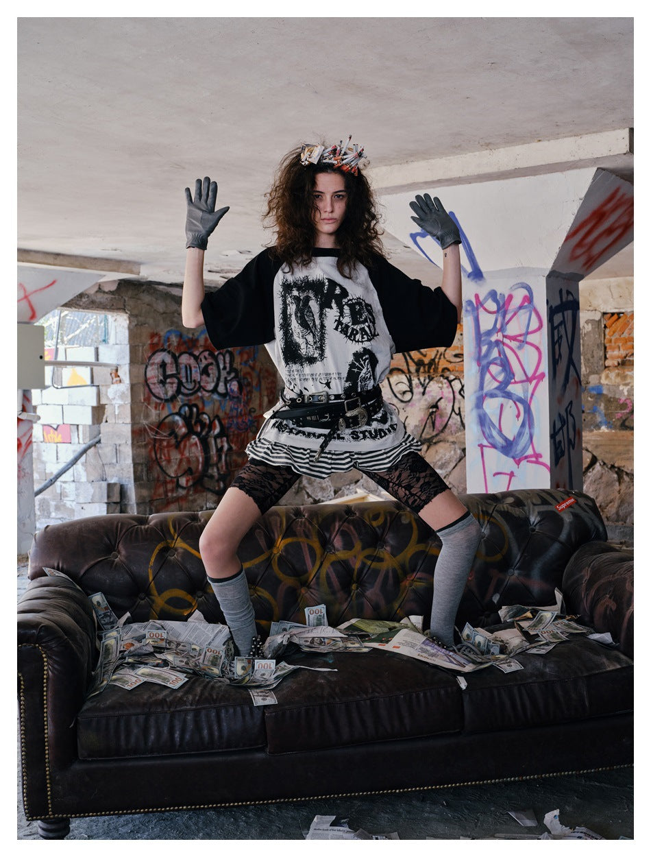 Full-length view of a model wearing a graphic black-and-white raglan T-shirt, striped skirt, gloves and gray socks.
