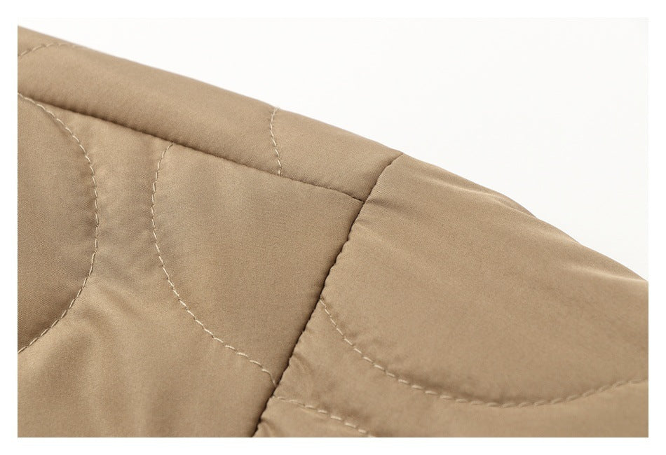 Close-up of curved stitching on a tan quilted jacket panel.