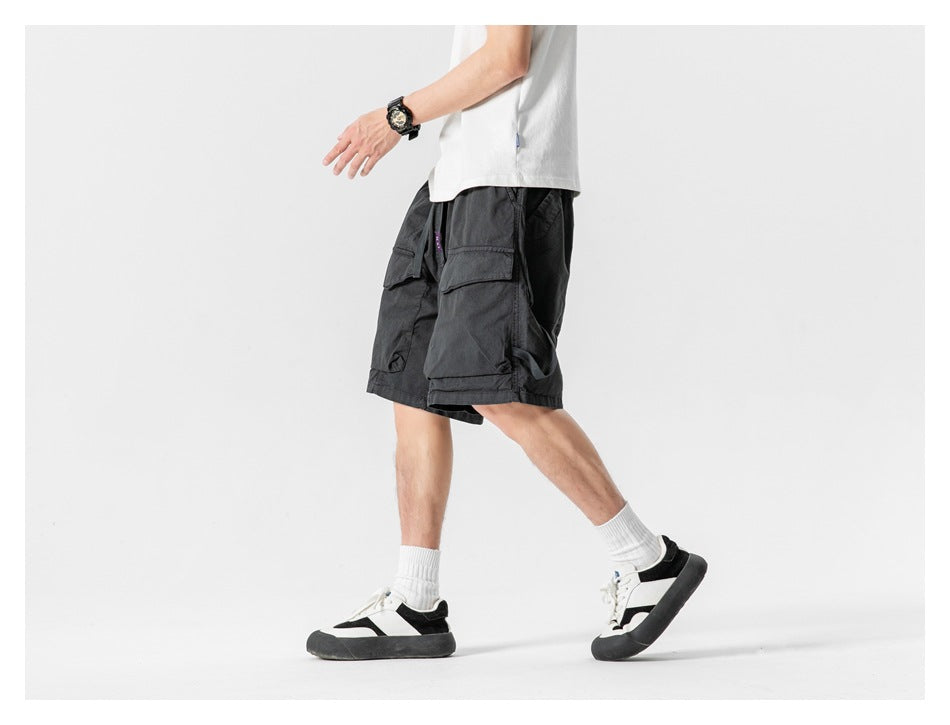 Side view of a model walking in black cargo shorts with oversized flap pockets.
