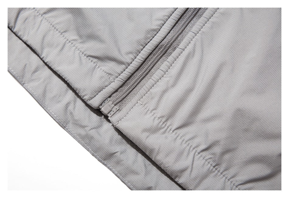 Close-up of the lower end of a zipper and hem stitching on the light gray jacket.