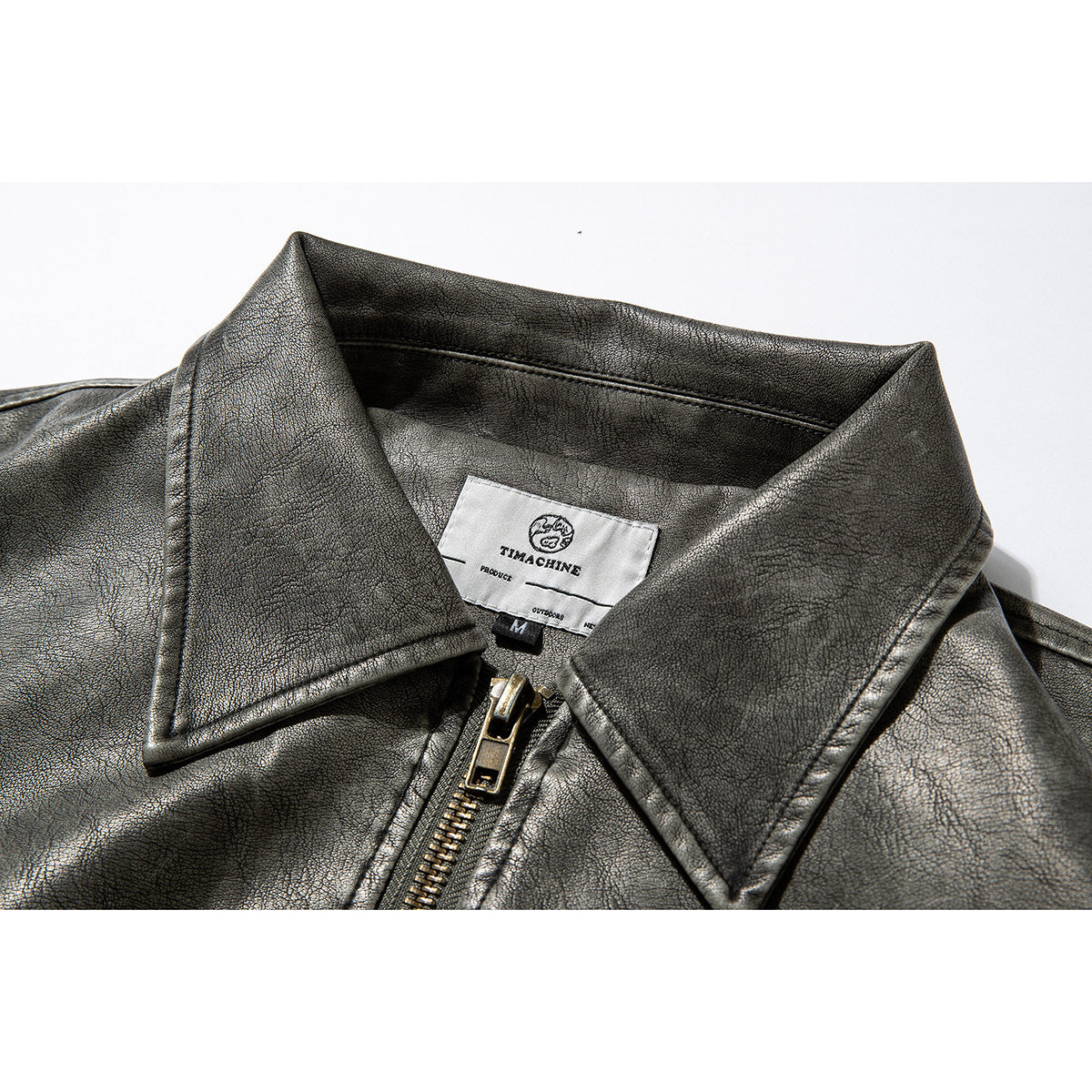 Close-up of a charcoal-gray jacket's pointed collar, zipper, and sewn neck label.