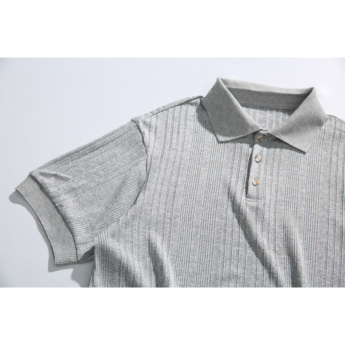Close view of a light gray ribbed polo shirt front, showing its collar, three-button placket, and short sleeve.