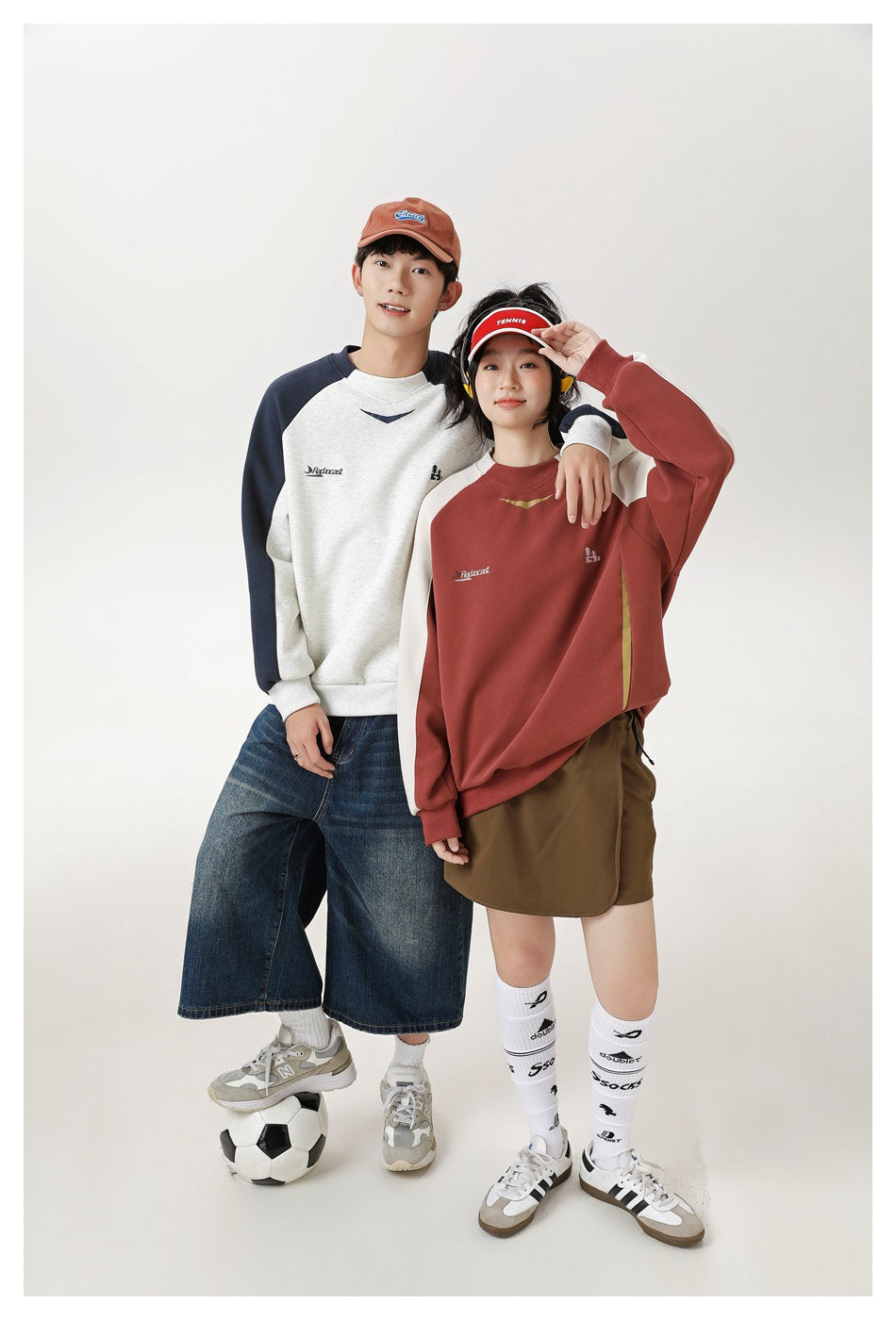 Two models pose in cream-and-navy and rust-and-cream raglan sweatshirts with casual bottoms.