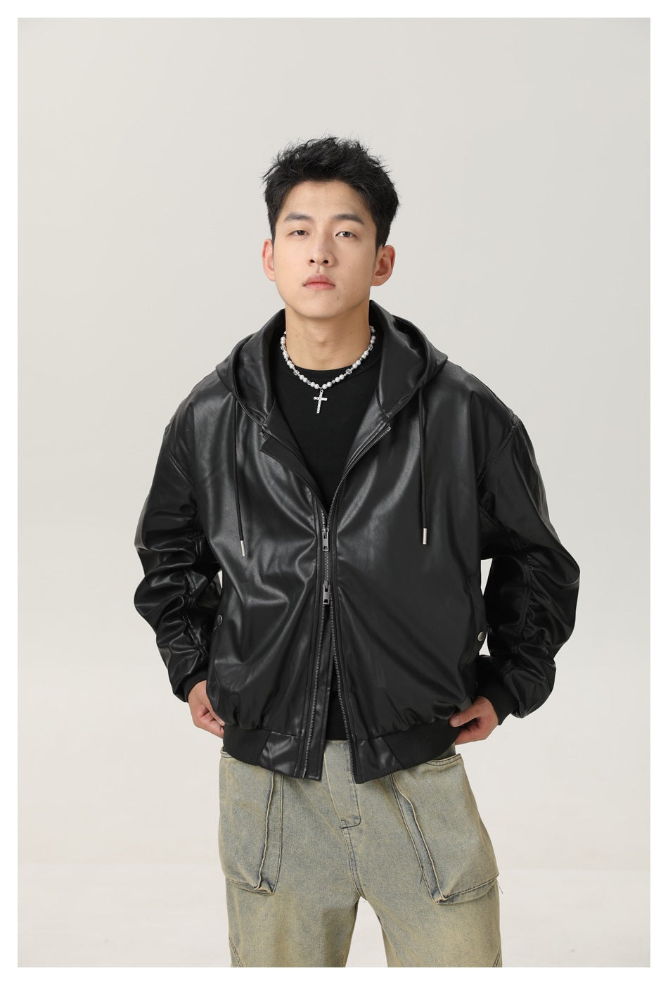 Front view of a model wearing an oversized black glossy hooded jacket with a zip front and ribbed hem.