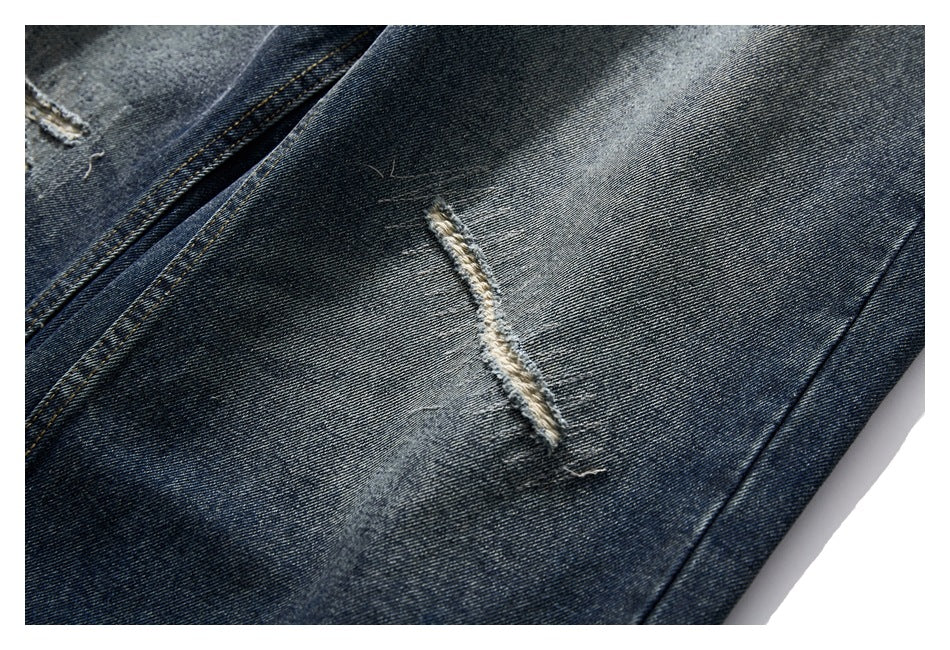 Close-up of dark washed denim showing a long frayed slash and faded areas.