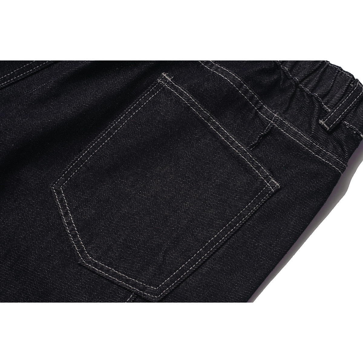 Close-up of a back pocket on dark indigo jeans with contrast stitching.