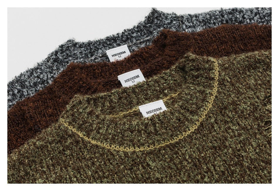 Close view of olive, brown, and gray marled sweaters layered together, showing their necklines and sewn labels.