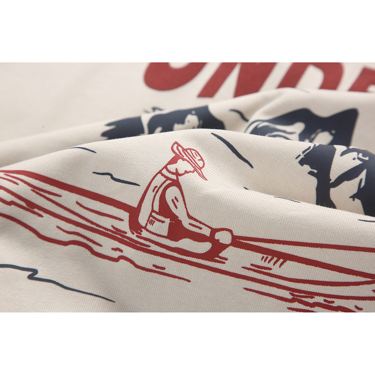 Close-up of a cream T-shirt printed with a red illustration and dark graphic elements.