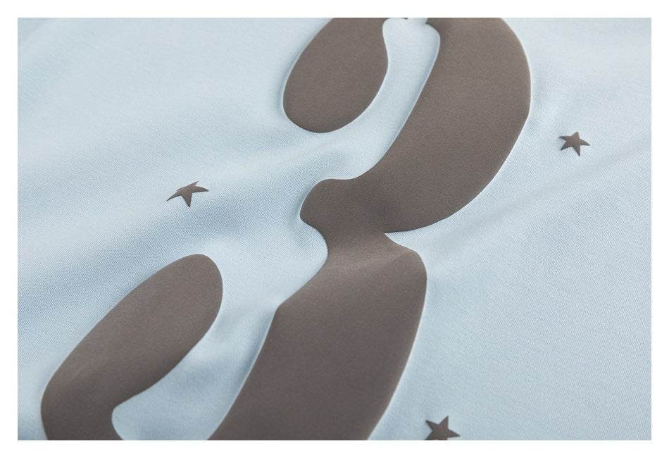 Extreme close-up of the charcoal number 3 and star print on light blue T-shirt fabric.