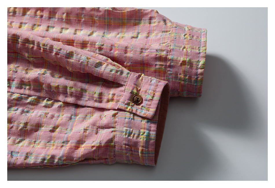 Close-up of the pink plaid jacket sleeve, buttoned cuff, and gathered hem.