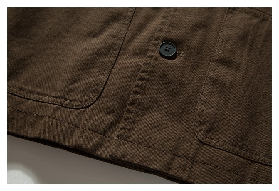 Close-up of brown garment pockets, a black button, and a stitched lower hem.