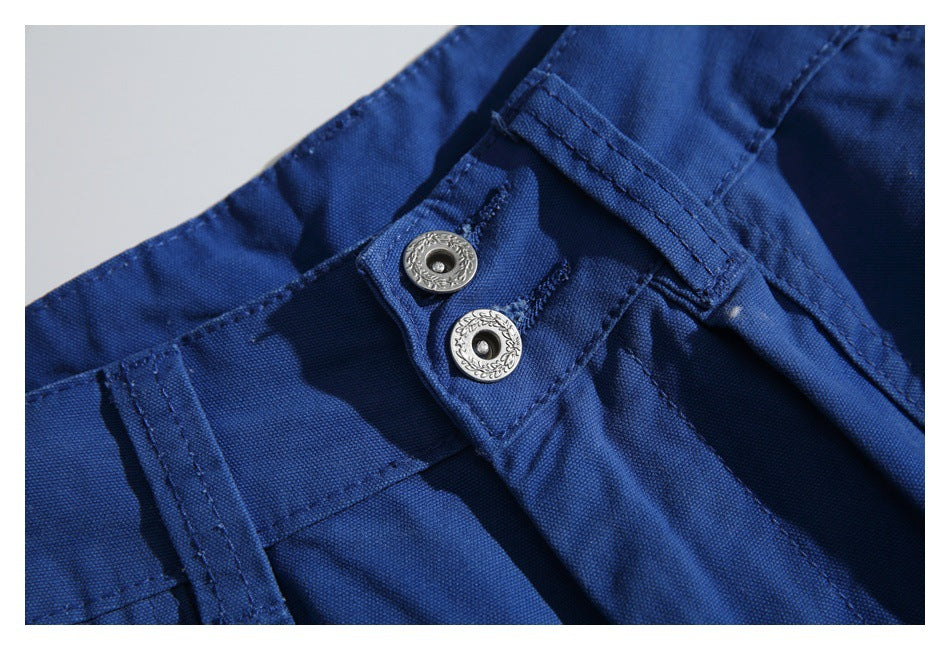 Close-up of the cobalt-blue trouser waistband with belt loop and two ornate silver-tone buttons.