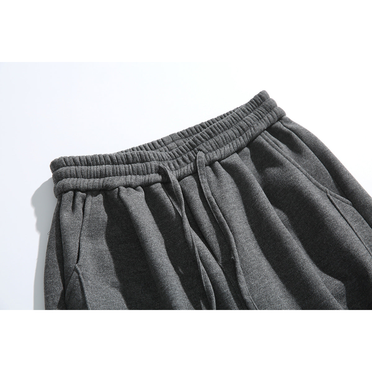 Close-up of charcoal pants showing the gathered elastic waistband and drawstring.