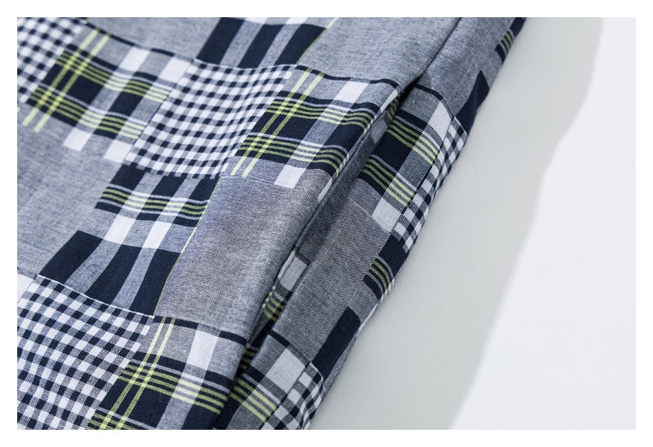 Close-up of gray, navy, white, and lime plaid fabric with mixed check patterns and a folded seam.