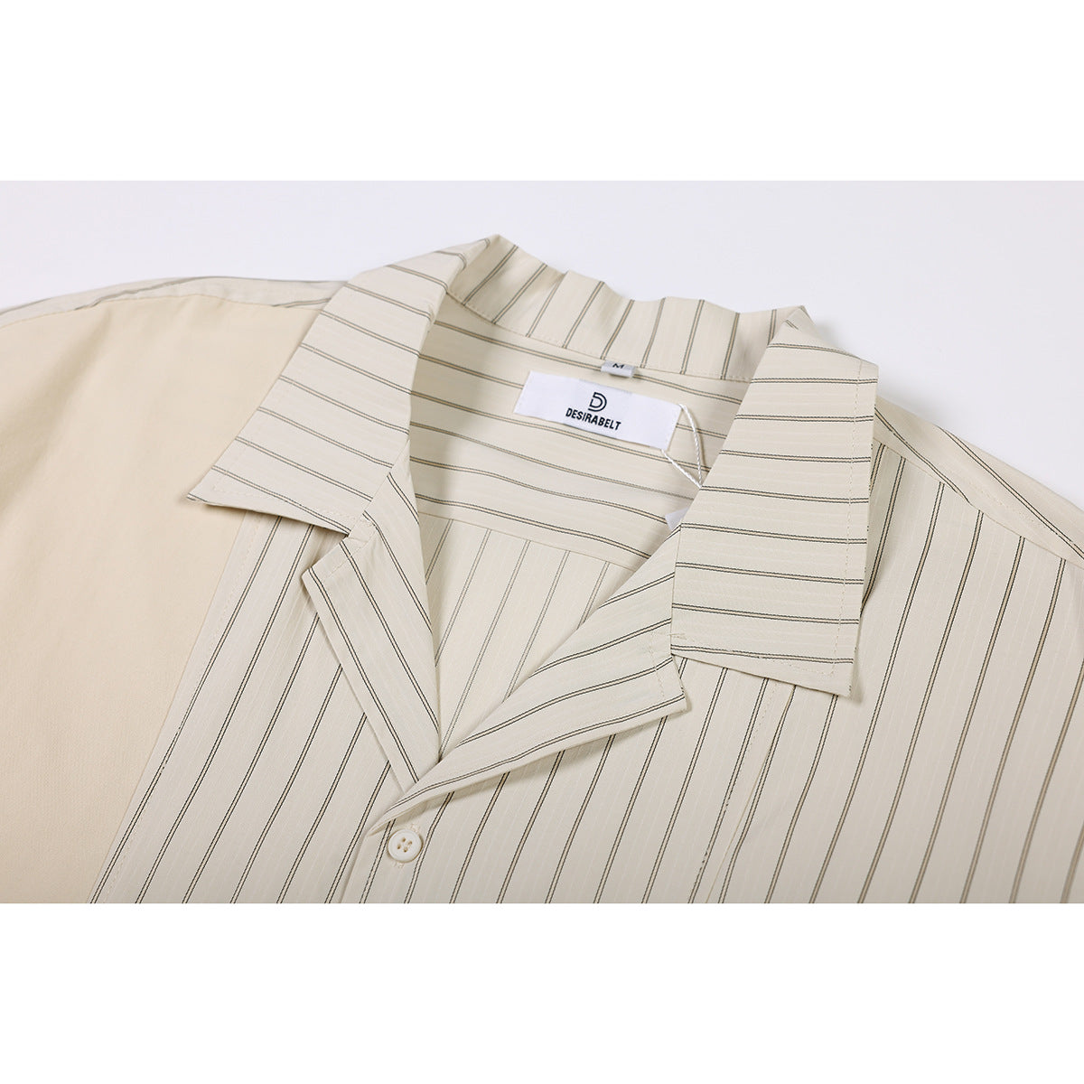 Close-up of a cream short-sleeve shirt with fine dark stripes, showing its wide collar, button, and inner neck label.