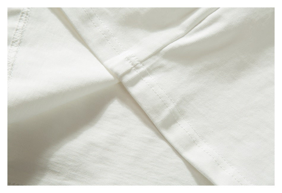 Close-up of intersecting stitched seams on white garment fabric.