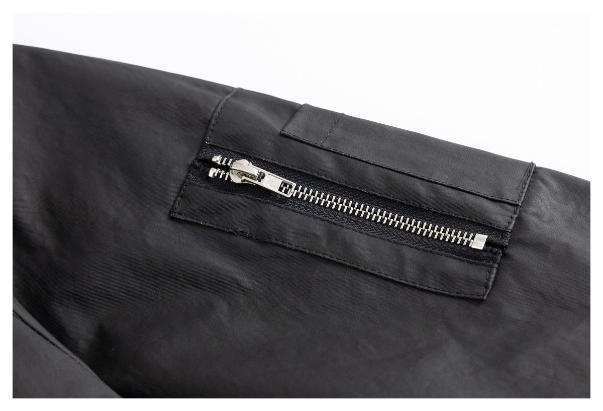 Close-up of a rectangular black pocket with a prominent silver zipper.