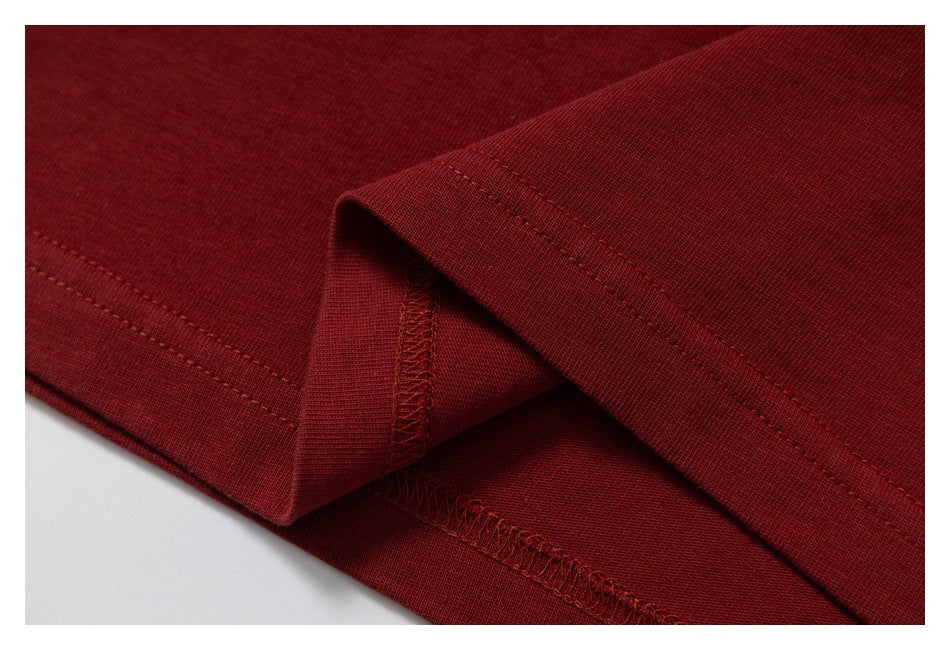 Close-up of a deep burgundy garment hem with visible stitching and overlocked seam finish.