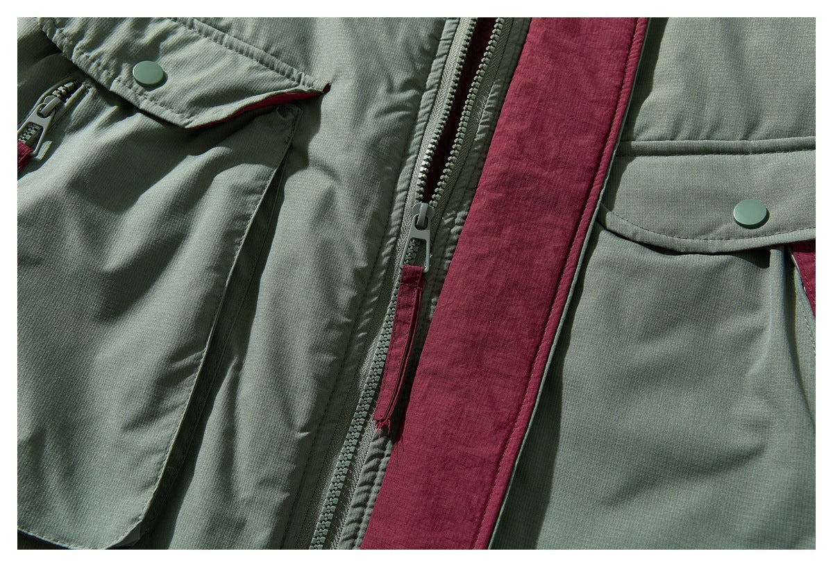 Close-up of the sage green jacket front, showing snap-flap pockets, a central zipper, and burgundy trim.