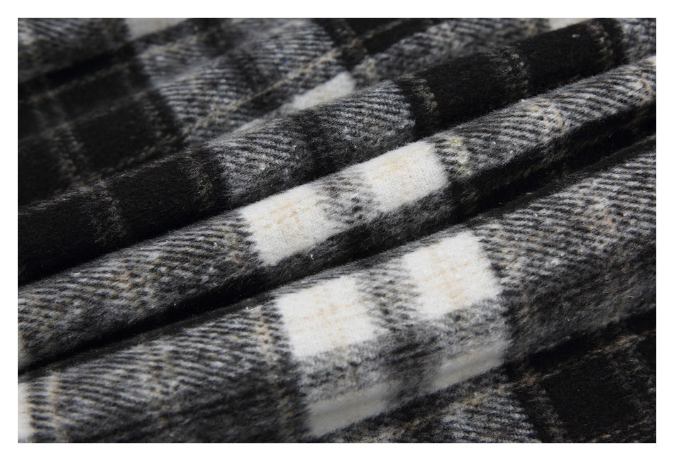 Close-up of folded black, gray, and cream plaid fabric.