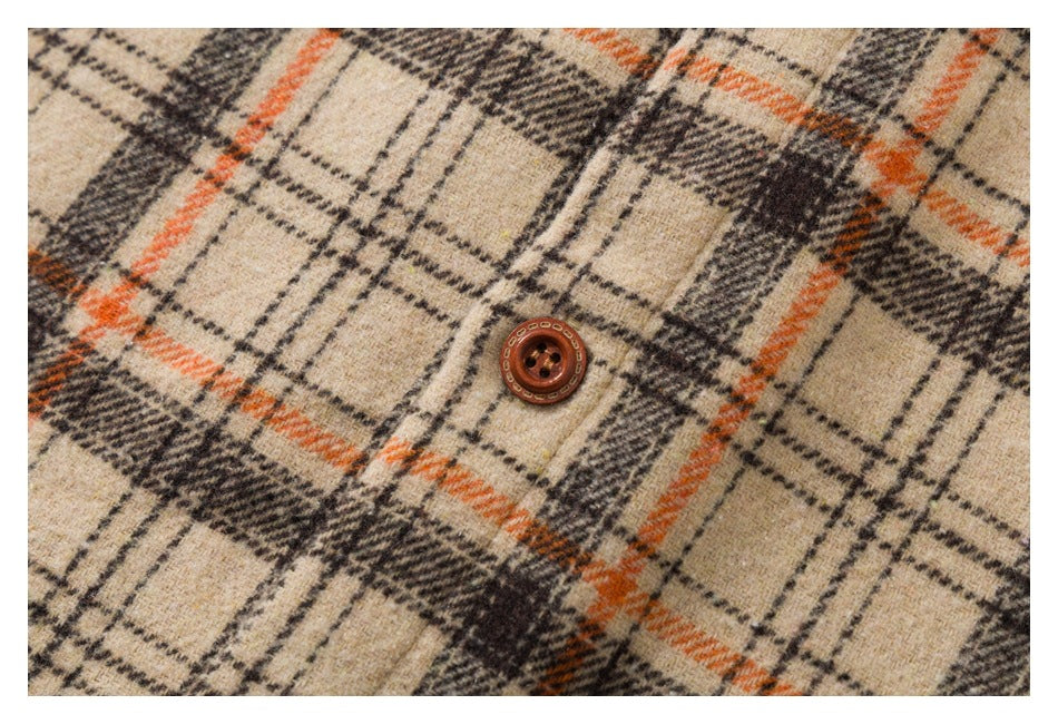 Close-up of a brown button on beige plaid fabric with orange and dark lines.