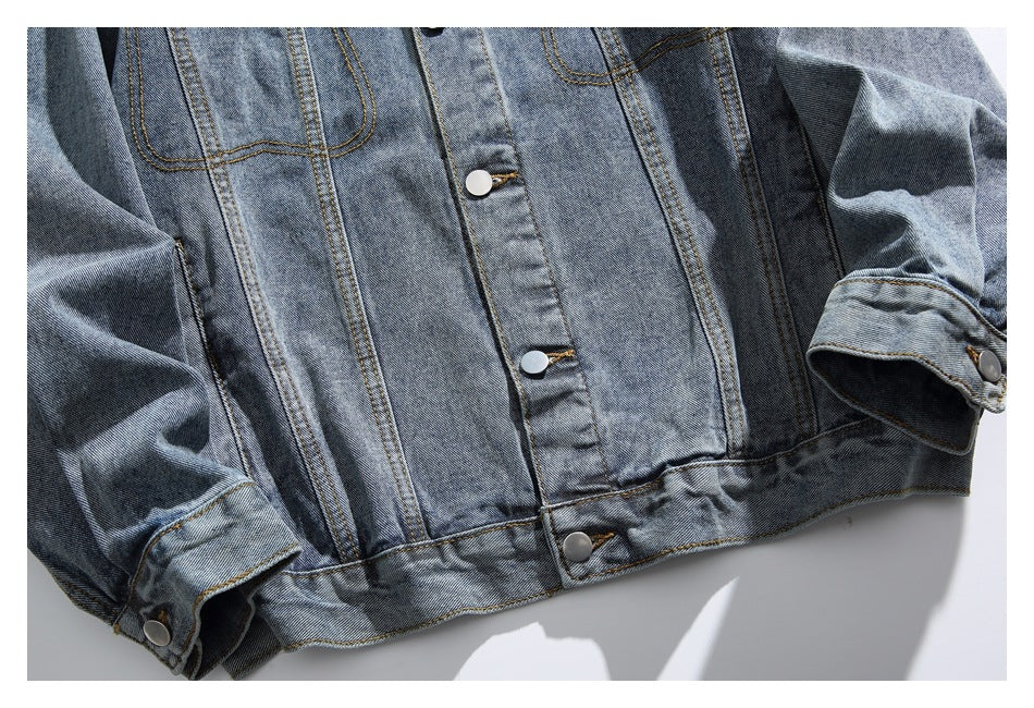 Cropped front view of a blue denim jacket showing its snap-button placket, seams, and buttoned cuffs.