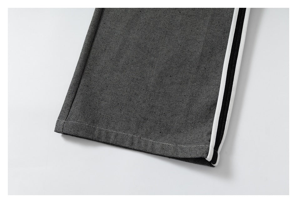 Close-up of the gray trouser leg hem with black-and-white side piping.
