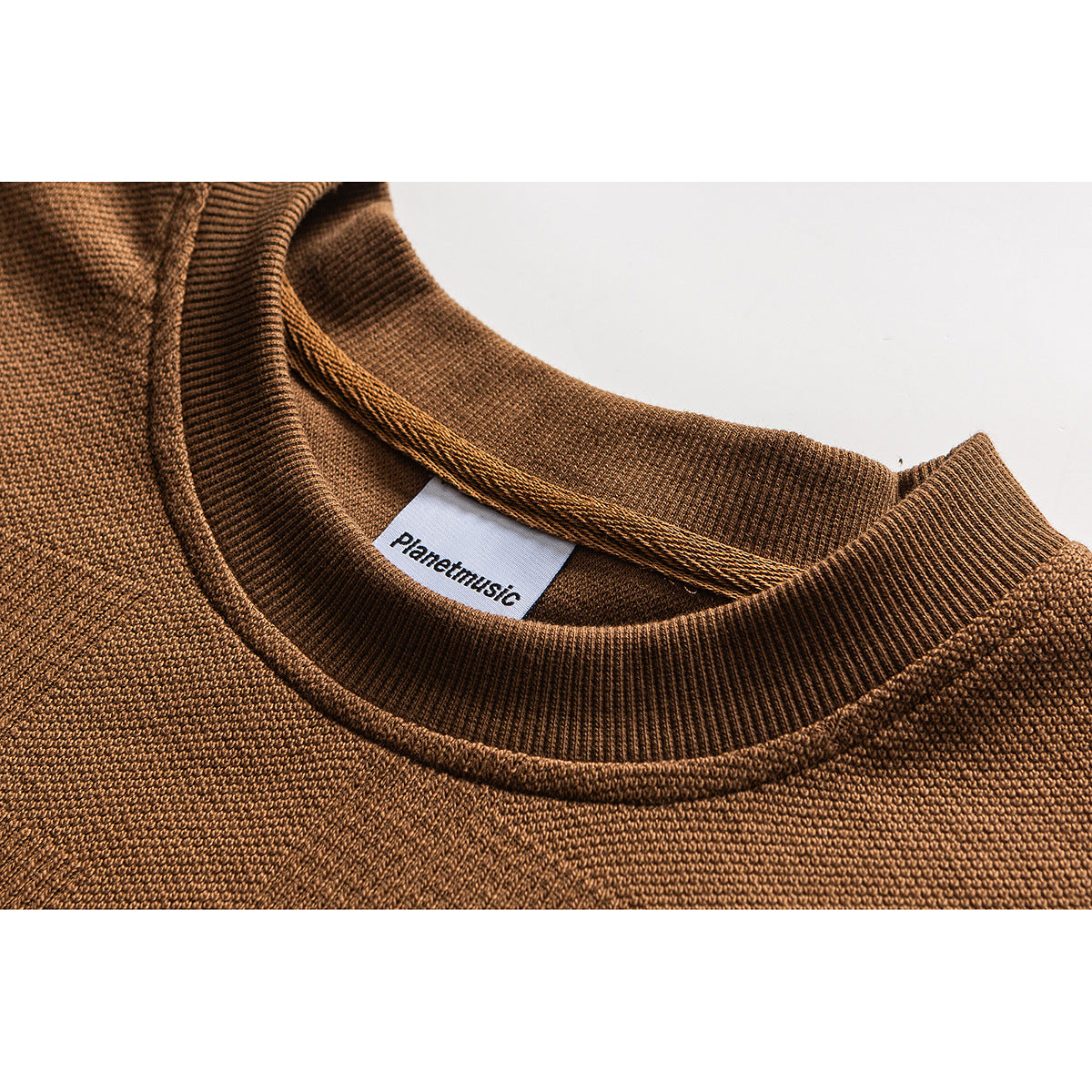 Close-up of a camel-brown knit top's ribbed crew neck and inner brand label.