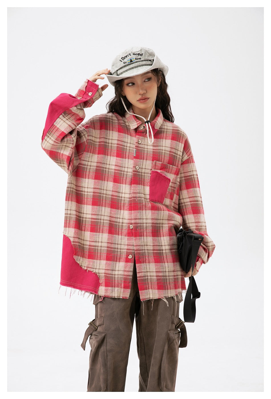 Fuller view of a model in an oversized red plaid shirt with pink contrast panels and a frayed hem.