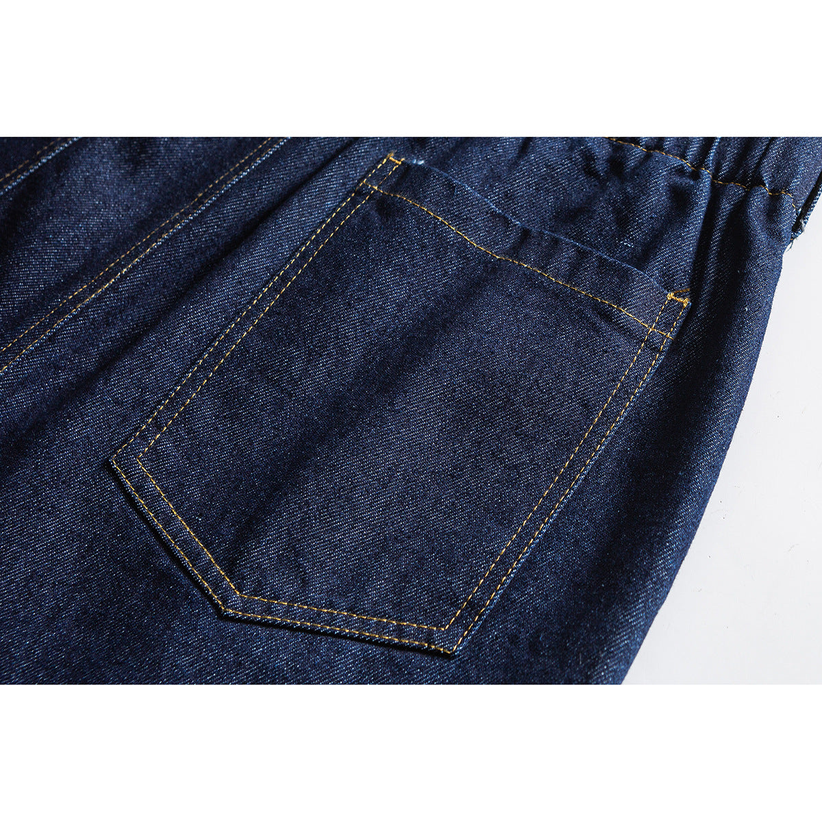 Close-up of a dark indigo jeans back pocket with golden-brown stitching and an elastic waist edge.