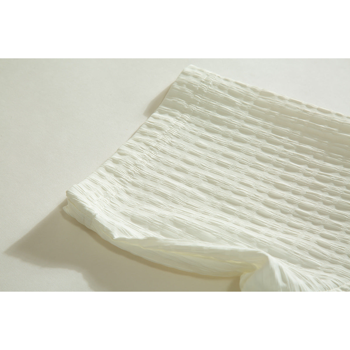 Close-up of the folded edge and textured fabric of an ivory shirt.