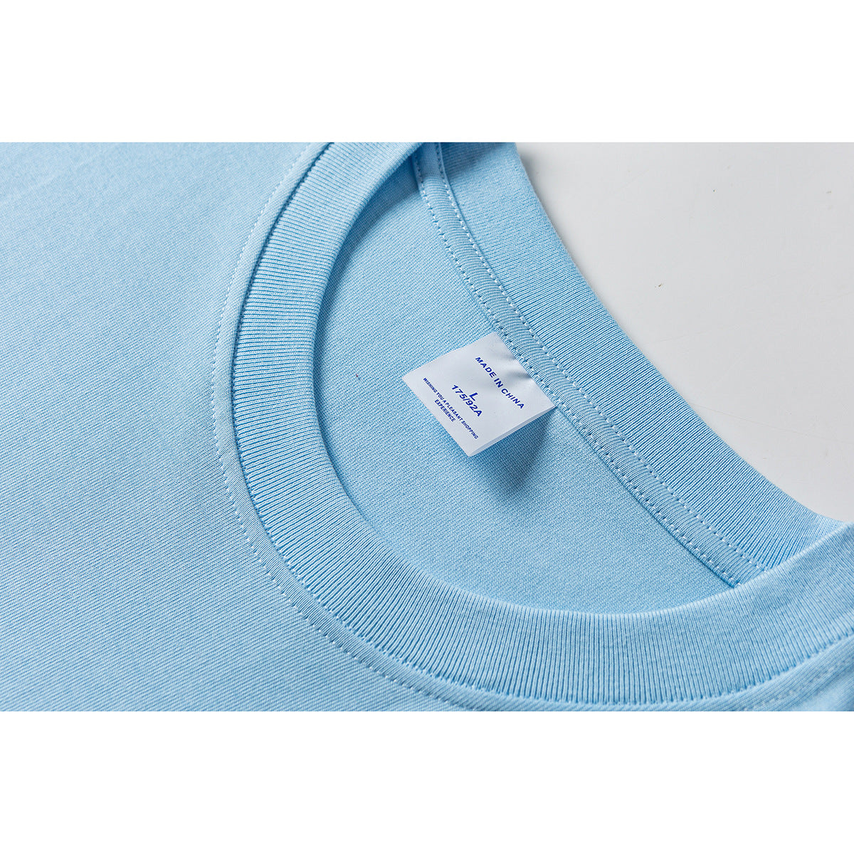 Close-up of a light blue T-shirt's ribbed crew neck and inner label.