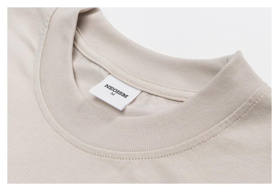 Close-up of the beige T-shirt's ribbed crew neck, stitching, and sewn NEOSISM label.