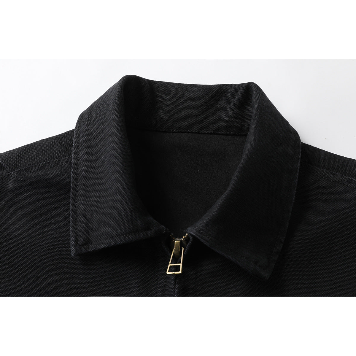 Close-up of a black jacket's pointed collar and front zipper with a gold-tone pull.
