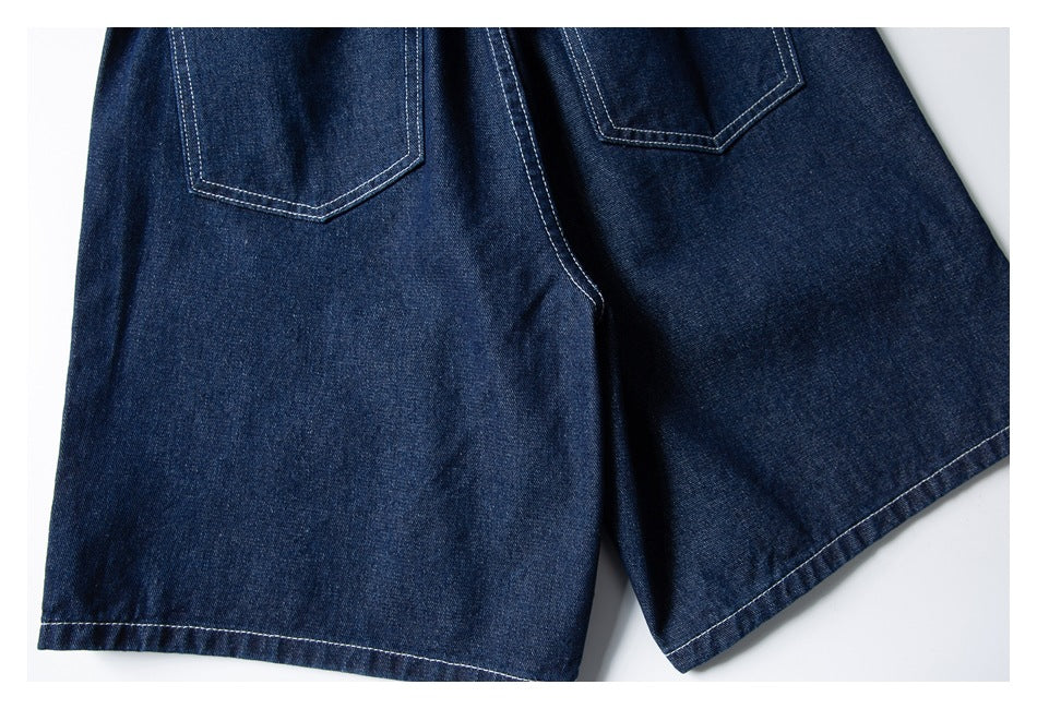 Close view of dark indigo denim shorts from the back, showing two patch pockets and contrast stitching.