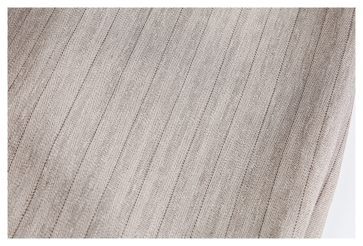 Close-up of beige-gray fabric with narrow dark vertical stripes.