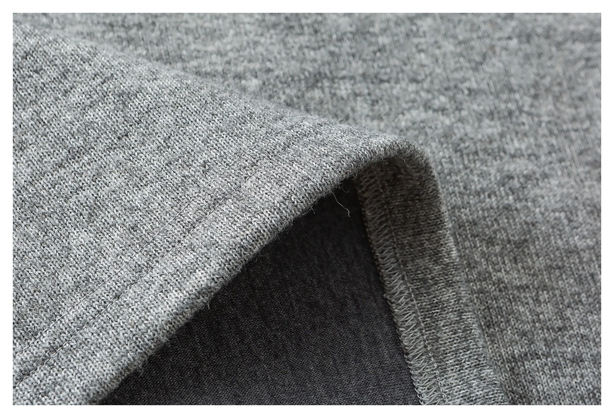 Close-up of heather gray knit fabric folded at a stitched edge, showing the seam and darker underside.
