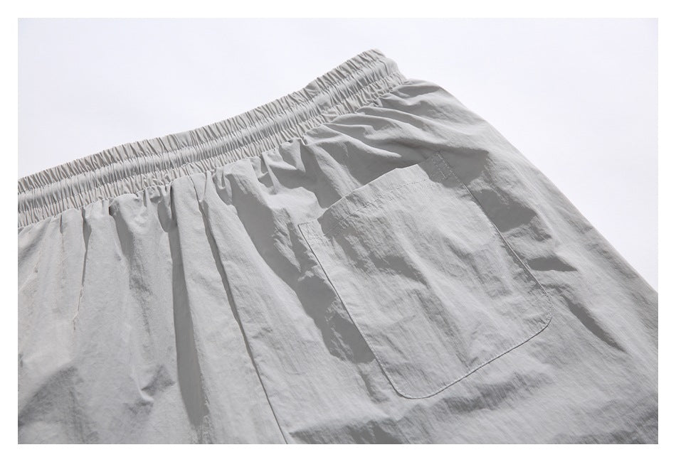 Close-up of light gray shorts showing the elastic waistband and a rectangular patch pocket.